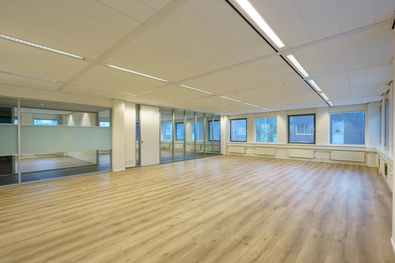 Licht en ruim leeg kantoor met houten vloer aan de Baarnsche Dijk.